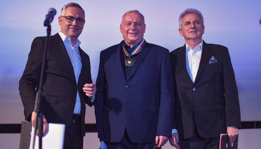 Trzech mężczyzn, w środku Roman Gutek z medalem Gloria Artis