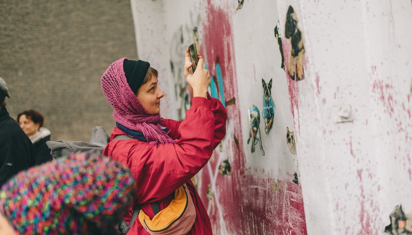 Sztuka na podwórkach. Kobieta fotografująca smartfonem fragment muralu, zdjęcie archiwalne.
