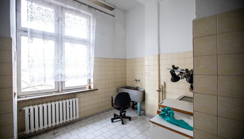 Czarne krzesło na kółkach w opuszczonym pomieszczeniu kliniki na Bujwida