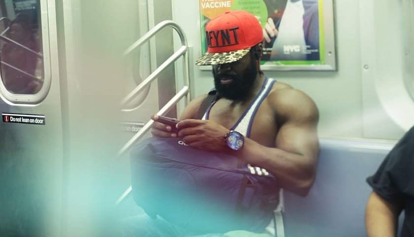 <p>Mężczyzna w koszulce na ramiączkach siedzący w metrze - kadr z filmu "21 x Nowy Jork"</p>