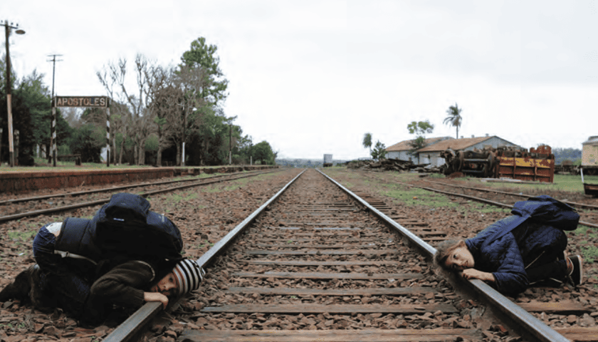 <p>Mężczyzna i kobieta przykładający ucho do tor&oacute;w kolejowych - kadr z filmu "Argentyńska lekcja"</p>