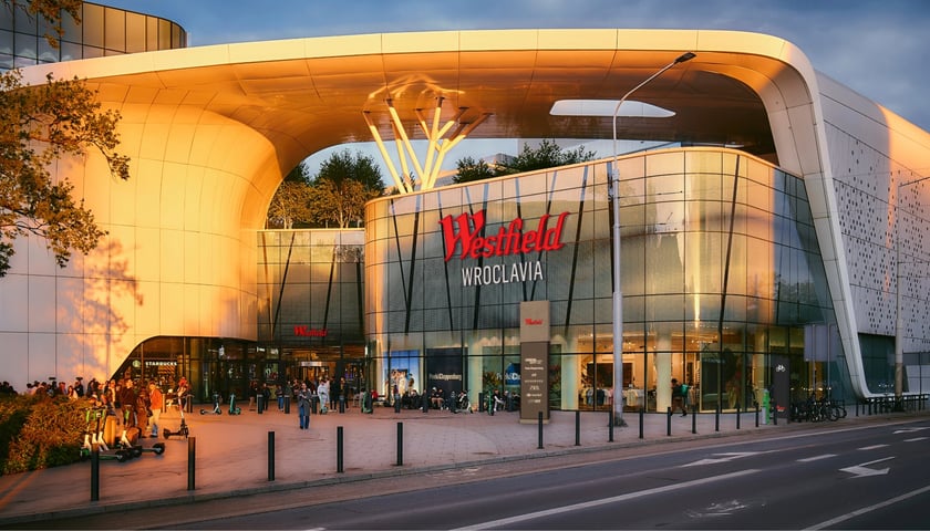 Wizualizacja przedstawiająca budynek centrum handlowego Wroclavia, na którym widnieje nowe logo: czerwony napis Westfield oraz biały dopisek Wroclavia