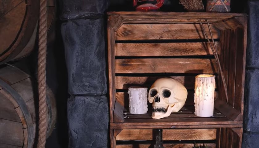 Na zdjęciu: czaszka i dwie świece w skrzynce, obok beczki i lina
