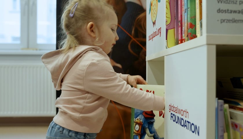 Dziewczynka przy regale z książkami 