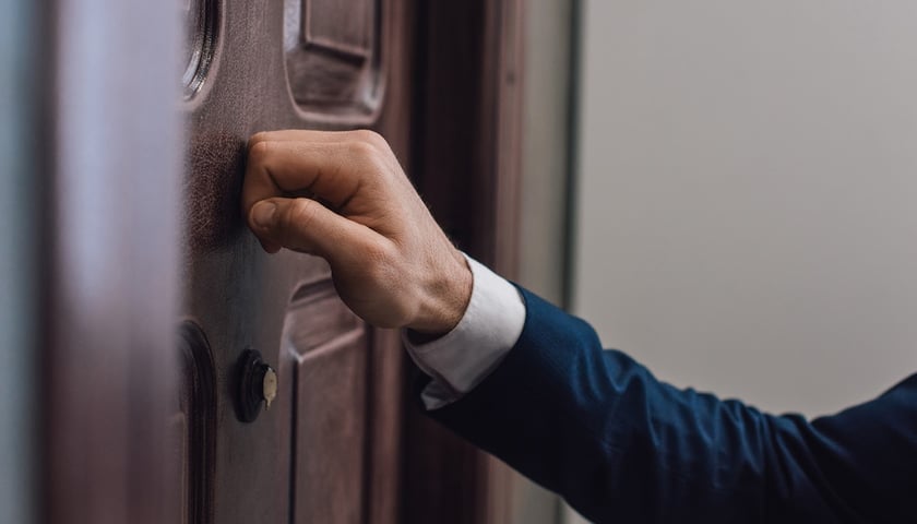 ZUS kontroluje osoby przebywające na zwolnieniach lekarskich. Na zdjęciu dłoń pukająca w drzwi / zdjęcie ilustracyjne