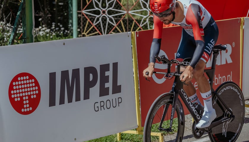 Kolarz na trasie Tour de Pologne. W tle baner z napisem "Impel Group"