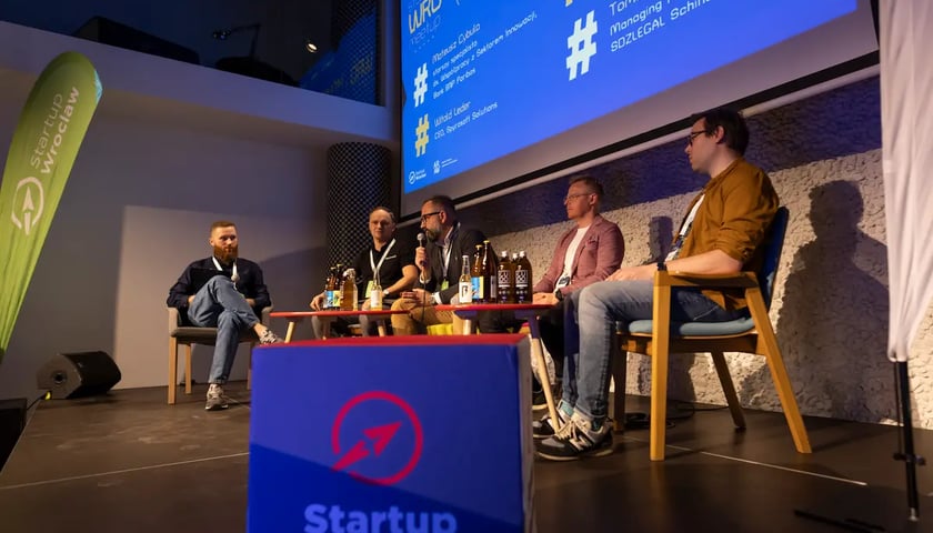 Archiwalne zdjęcie ze Startup WRO Meetup. Kilka osób siedzi na krzesłach na scenie
