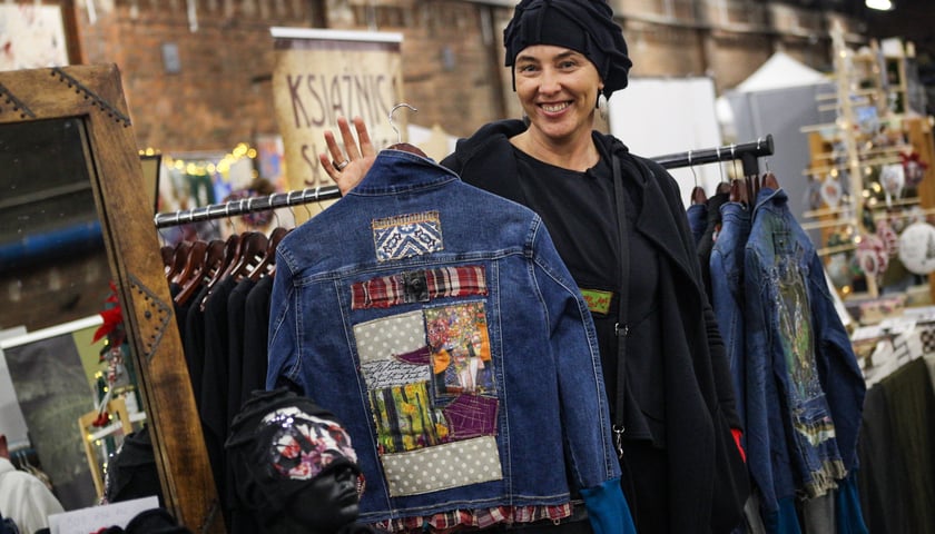 Kobieta pokazuje kurtkę na jedynym ze stoisk Targów Jedynych w Swoim Rodzaju