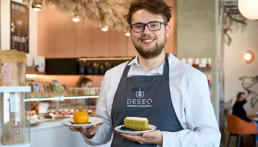 Nataniel, menadżer cukierni DESEO z ciastkami na talerzykach