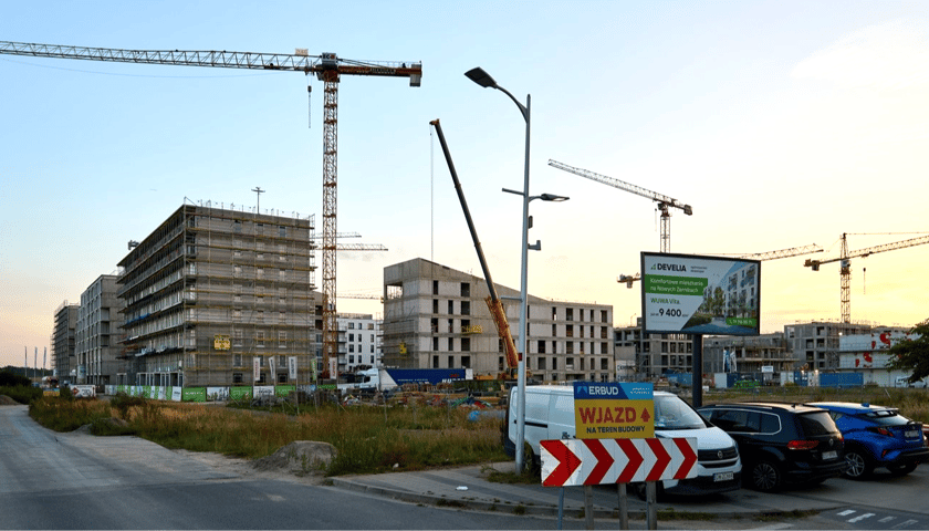 Budowa budynków mieszkalnych, zaparkowane przy ulicy samochody, w tle dźwigi. Nowa inwestycja mieszkaniowa na Nowych Żernikach we Wrocławiu, wrzesień 2025 r.