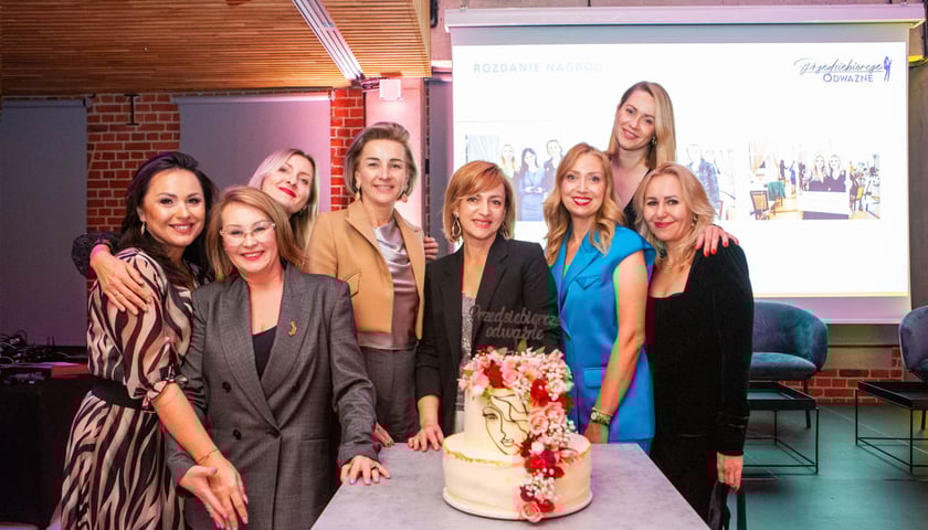 Osiem kobiet, uśmiechają się, przed nimi na stole jest tort. Przedsiębiorcze kobiety spotkają się we Wrocławiu po raz trzeci