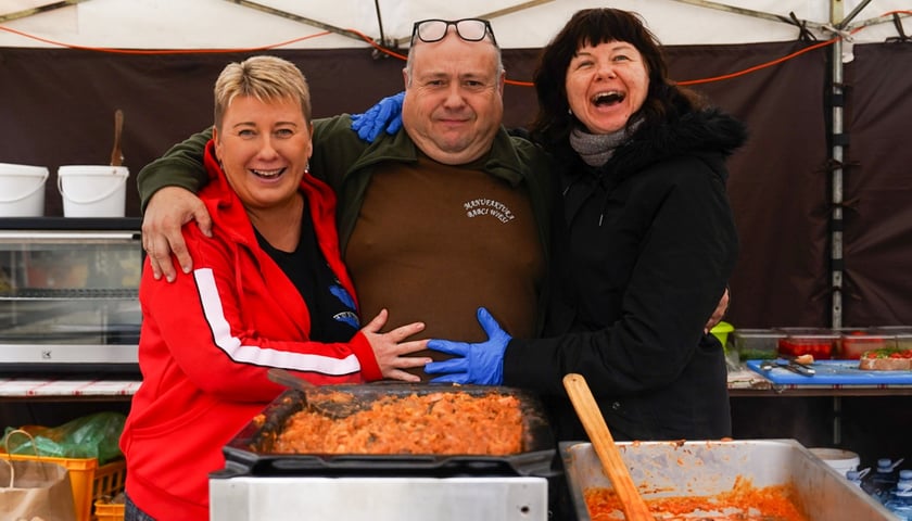 Uśmiechnięte dwie kobiety i mężczyzna, w tle różne potrawy. Uczestnicy Wrocławskiego Oktoberfest  na placu Nowy Targ, 11.10.2025 r.