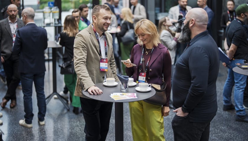 Ludzie przy stolikach rozmawiający w ramach networkingu