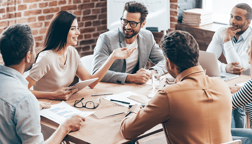 Kobiety i mężczyźni siedzą przy stole, zdjęcie ilustracyjne.  