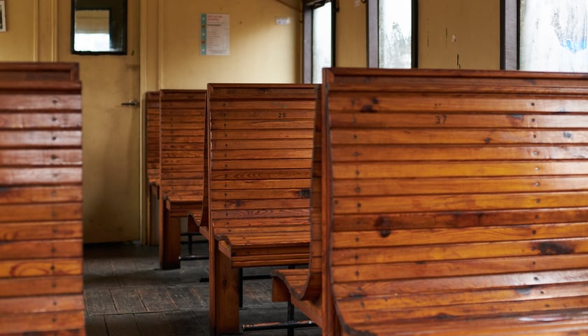 Drewniane ławki pasażerskie wewnątrz zabytkowego wagonu kolejowego