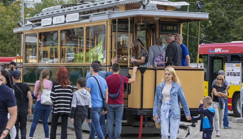 Powiększ obraz: Dzień Otwarty Zajezdni Popowice, zdjęcie archiwalne. W centrum kadru zabytkowy tramwaj Maximum z 1903 roku , oglądany przez zwiedzających.
