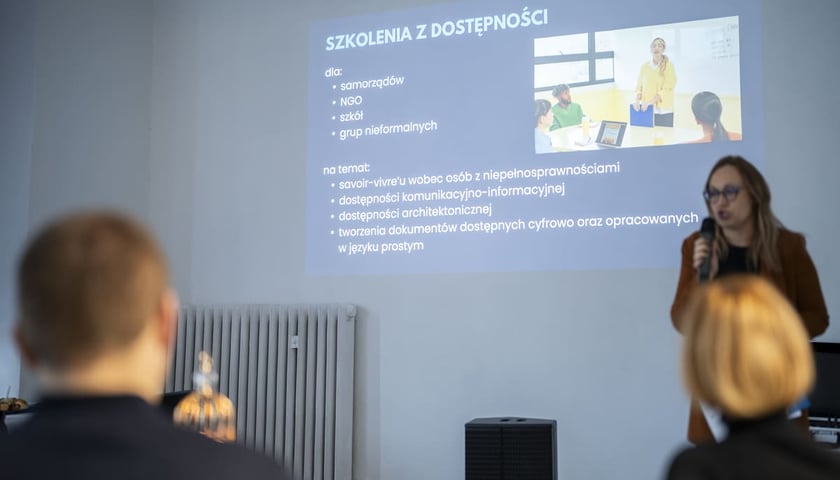 Powiększ obraz: <p>Otwarcie Centrum Edukacyjno-Treningowego przy placu Legionów 1-2. Wrocław, 15.01.2025. W tle slajd prezentacji o szkoleniach z dostępności, przy mikrofonie Joanna Burkiewicz</p>