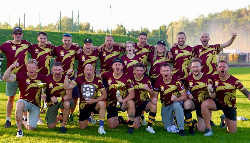 Powiększ obraz: Radość drużyny Lions Wrocław po zdobyciu tytułu mistrza Polski sezonu 2025 w futbolu australijskim. Zawodnicy klęczą w przednim i stoją w tylnym rzędzie.