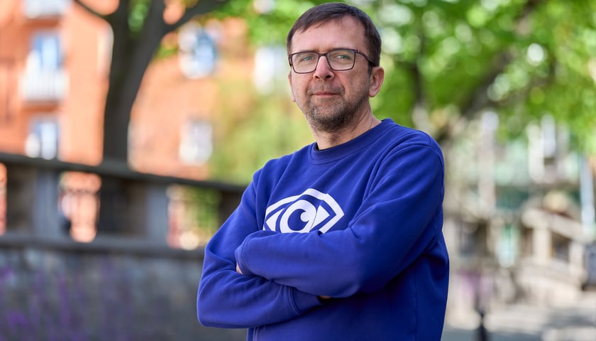 Mężczyzna w okularach na tle drzew i budynków - dr Krzysztof Chudy z Wydziału Geoinżynierii, Górnictwa i Geologii Politechniki Wrocławskiej, członek Stowarzyszenia Hydrogeologów Polskich, autor profilu „Okiem Hydrogeologa”.