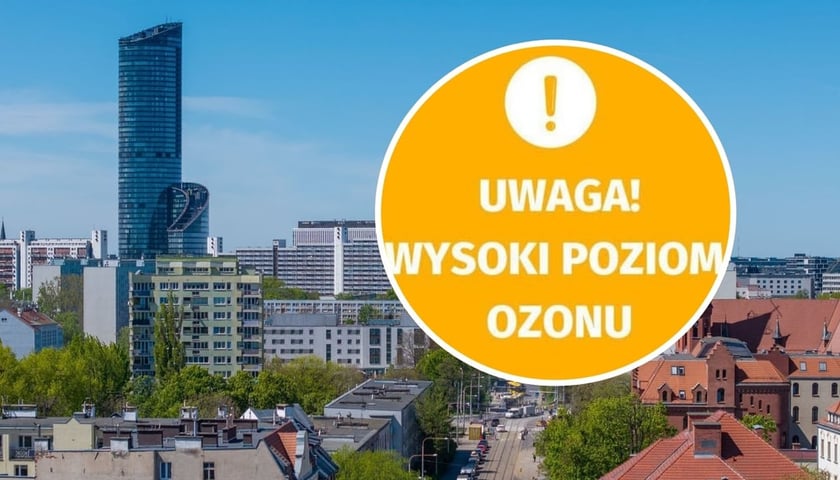 Zdjęcie ilustracyjne - widok na budynki ulice oraz Sky Tower we Wrocławiu w pogodny dzień - ujęcie z drona / w kółeczku napis "Uwaga! Wysoki poziom ozonu"
