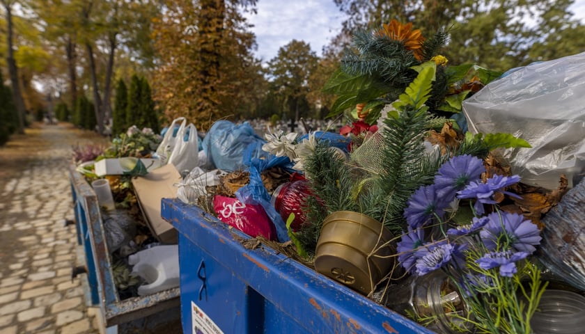 Na zdjęciu kontener na śmieci na cmentarzu wypełniony odpadami