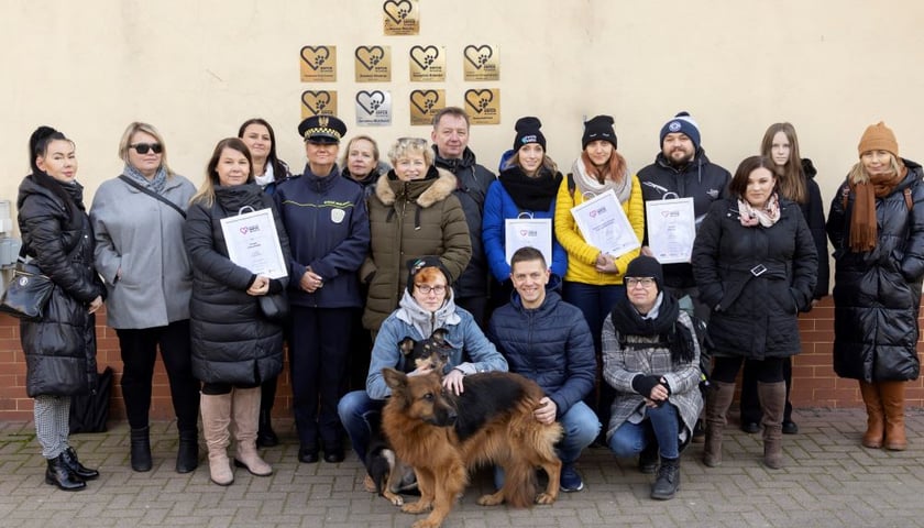 „Rodzinna” fotografia na tle ściany trybuny na partynickim torze, obrastającej nowymi tabliczkami, to miła tradycja Wrocławskiego Serca dla Zwierząt  