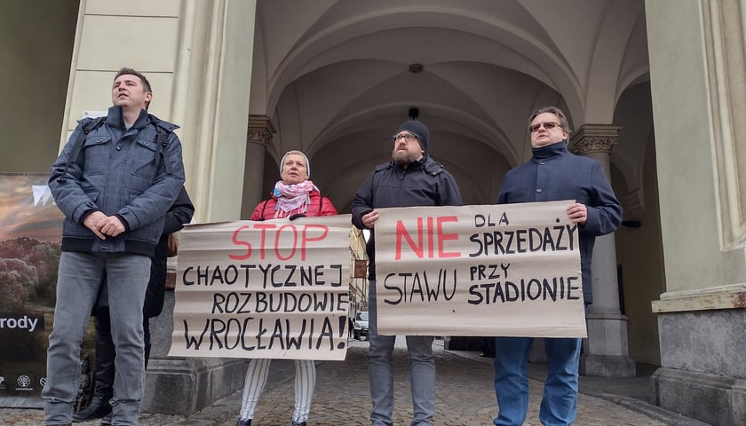 Na zdjęciu: czwórka osób protestujących z dwoma transparentami pod ratuszem