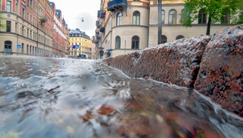 Na zdjęciu widać spływający strumień wody po ulicy