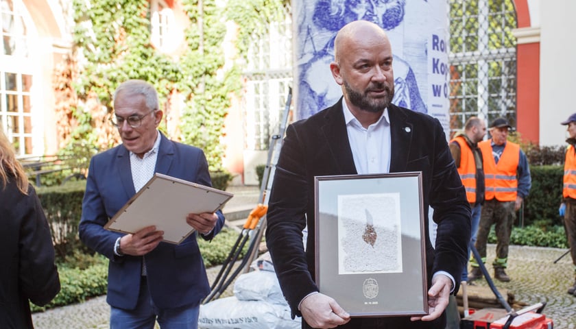 Pamiątkowy papier czerpany z wyciętego kasztanowca, otrzymał go stojący na pierwszym planie zdjęcia Jacek Sutryk. prezydent Wrocławia