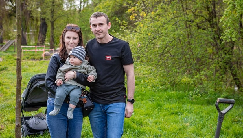 Na zdjęciu rodzina z dzieckiem przy posadzonym drzewku podczas akcji WROśnij we WROcław w parku na Niskich Łąkach
