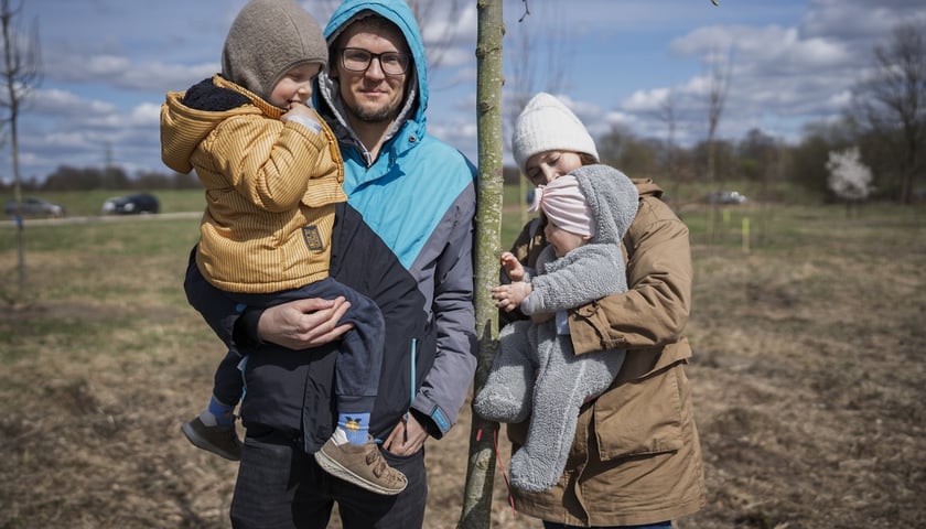 Piknik #WROśnijweWROcław przy ul. Lechitów. Na zdjęciu dwoje uśmiechniętych dorosłych i dwoje dzieci przy młodym drzewku