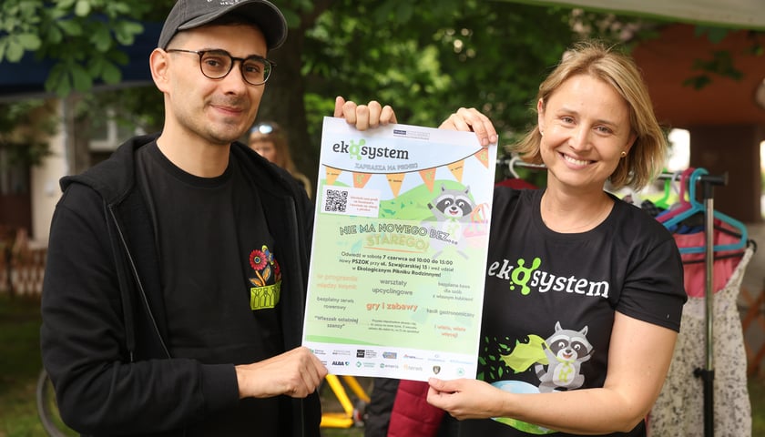 Kobieta i mężczyzna trzymający plakat z zaproszeniem na piknik Ekosystemu