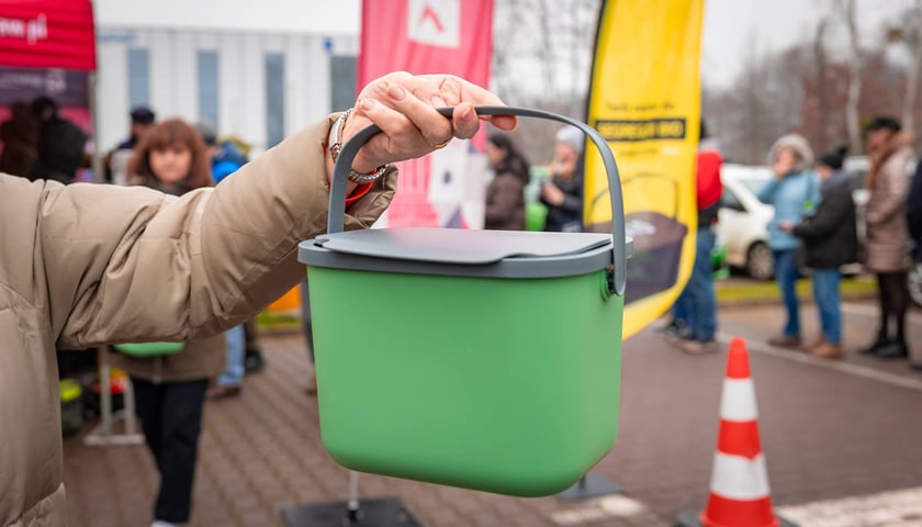 Ręka z pojemnikiem na bioodpady