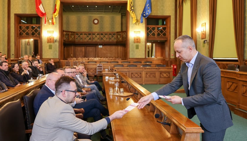 Wiceprezes MPWiK Przemysław Gałecki przekazuje materiały informacyjne deweloperom