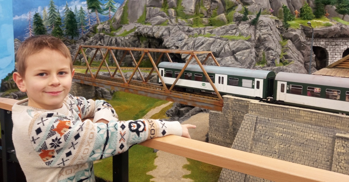 Chłopiec stojący obok dużej makiety kolejowej we wrocławskim Kolejkowie