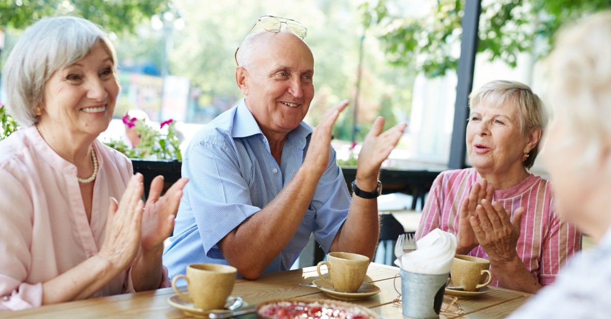 Czwórka seniorów pogodnie rozmawiających przy wspólnym stole