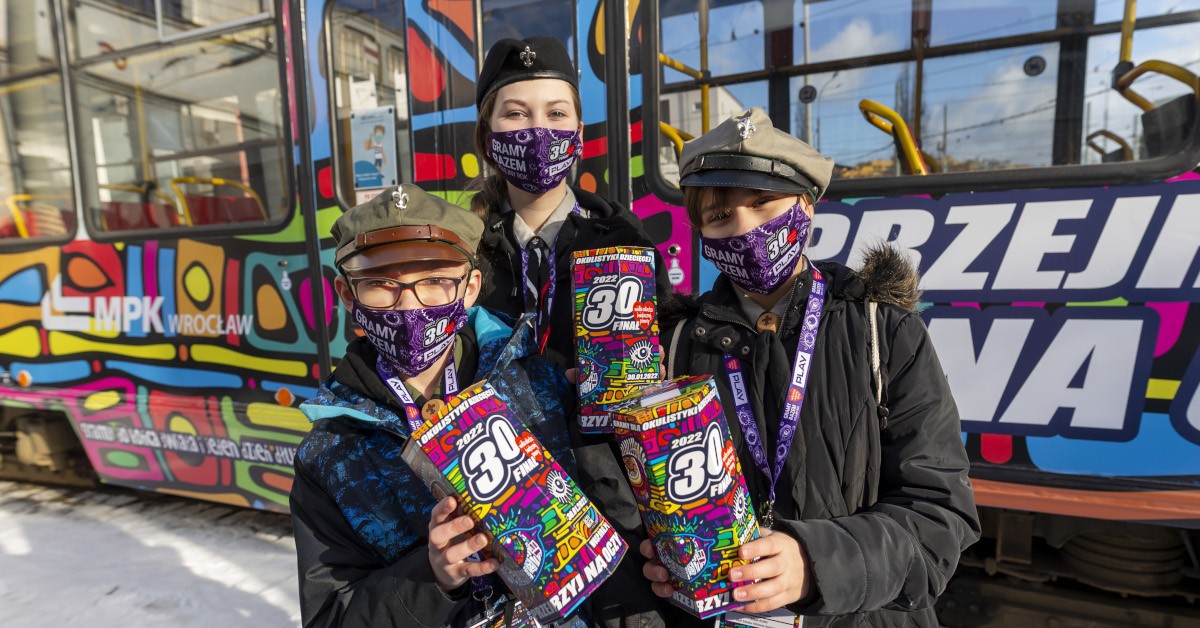 trójka wolontariuszy WOŚP ze skarbonkami i w maseczkach