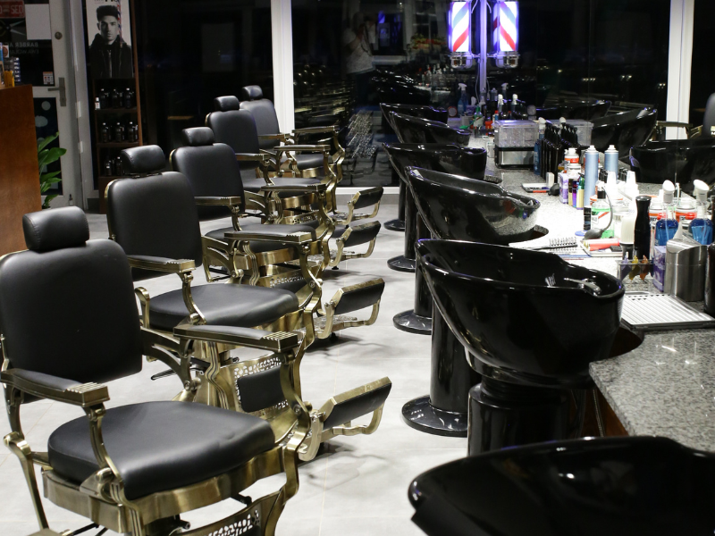 na zdjęciu pusty salon fryzjerski, rząd krzeseł, myjek i przyborów do strzyżenia włosów