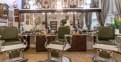 na zdjęciu pusty salon fryzjerski, zielone krzesła stoją przed lustrami 