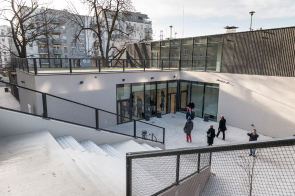 Na zdjęciu widnieje projekt Centrum Aktywności Lokalnej. Nowoczesny biały budynek, a po schodach na dół wejście do obiektu.