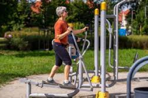 Na zdjęciu widnieje kobieta w wieku senioralnym, która ćwiczy na siłowni outdoorowej.